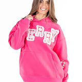 Woman wearing hot pink Simply Southern Merry appliqué hoodie with candy cane details at ooh la la! in Grapevine TX 76051