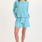 Woman wearing XCVI Elvio Shorts in mermaid tail pigment aqua blue with matching top