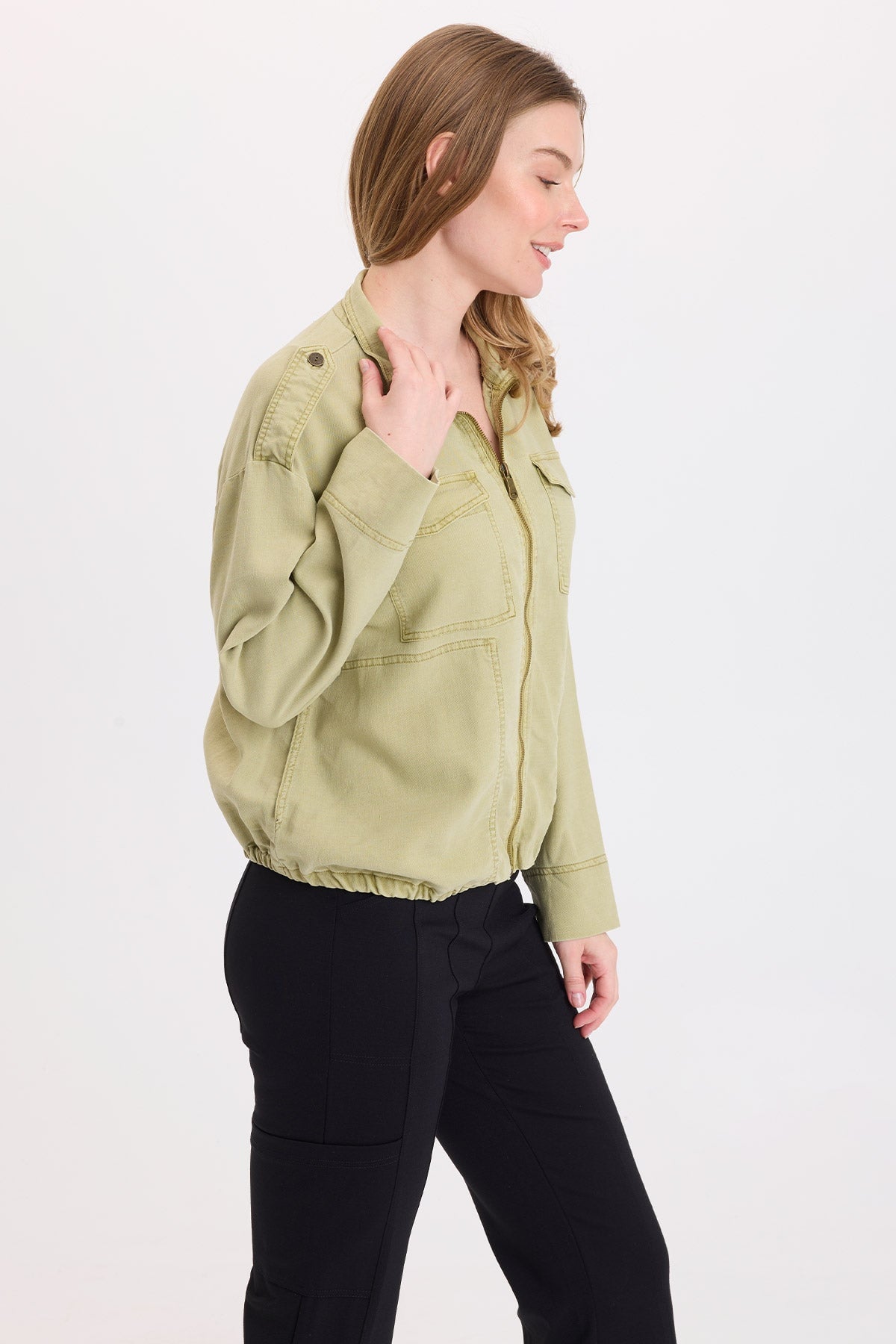 Woman wearing XCVI Tace Tencel Twill Relaxed Bomber Jacket in Artichoke Pigment with black pants