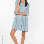 Bree Dress, Tencel lyocell dress, tiered mini dress, denim shirt dress, sustainable fashion, eco-friendly women's clothing, light blue chambray dress, tiered dress with pockets. at ooh la la! in Grapevine TX 76051