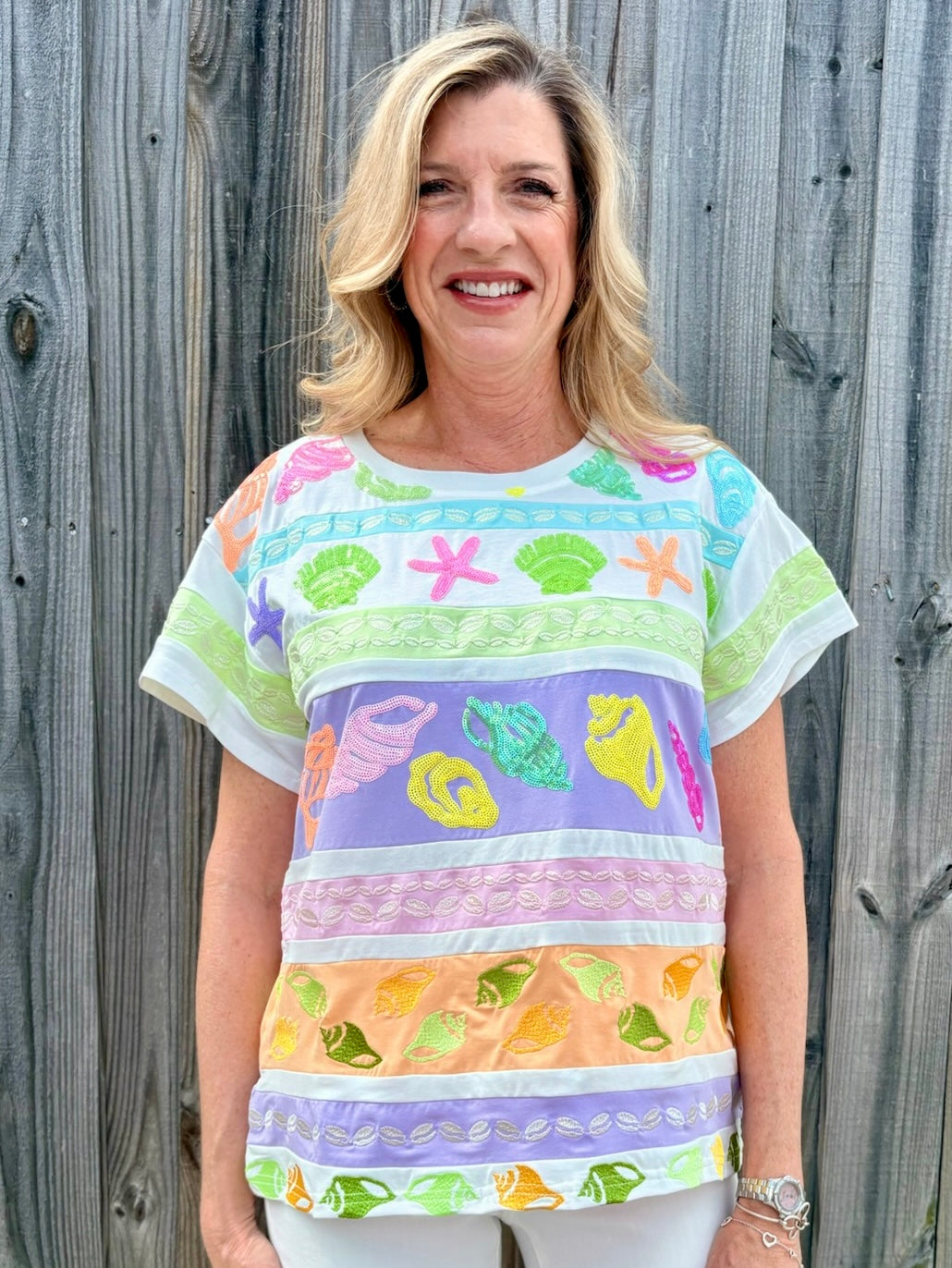 Queen of Sparkles, seashell sequin tee, pastel colorblock top, coastal vacation outfit, designer beach wear, sequin shell shirt, luxury summer fashion. at ooh la la! in Grapevine TX 76051