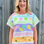 Queen of Sparkles, seashell sequin tee, pastel colorblock top, coastal vacation outfit, designer beach wear, sequin shell shirt, luxury summer fashion. at ooh la la! in Grapevine TX 76051