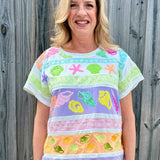 Queen of Sparkles, seashell sequin tee, pastel colorblock top, coastal vacation outfit, designer beach wear, sequin shell shirt, luxury summer fashion. at ooh la la! in Grapevine TX 76051