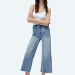 Woman wearing light blue high-rise wide-leg cropped jeans with white tank top