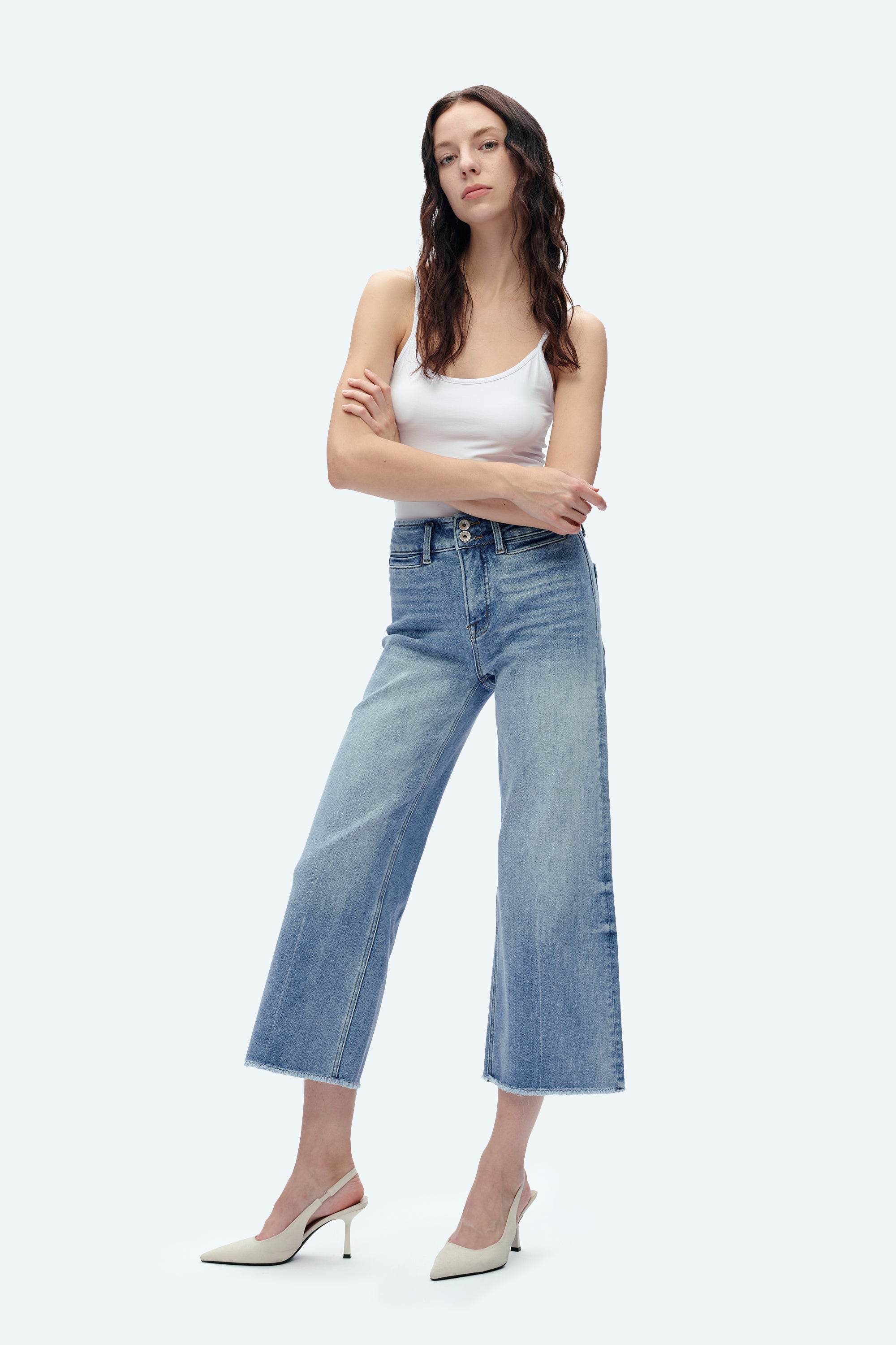 Woman wearing light blue high-rise wide-leg cropped jeans with white tank top