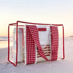 Clear tote bag with red gingham handles and ruffle details on beach sand