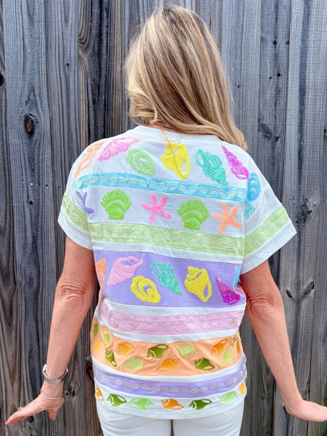 Queen of Sparkles, seashell sequin tee, pastel colorblock top, coastal vacation outfit, designer beach wear, sequin shell shirt, luxury summer fashion. at ooh la la! in Grapevine TX 76051