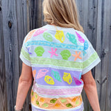 Queen of Sparkles, seashell sequin tee, pastel colorblock top, coastal vacation outfit, designer beach wear, sequin shell shirt, luxury summer fashion. at ooh la la! in Grapevine TX 76051