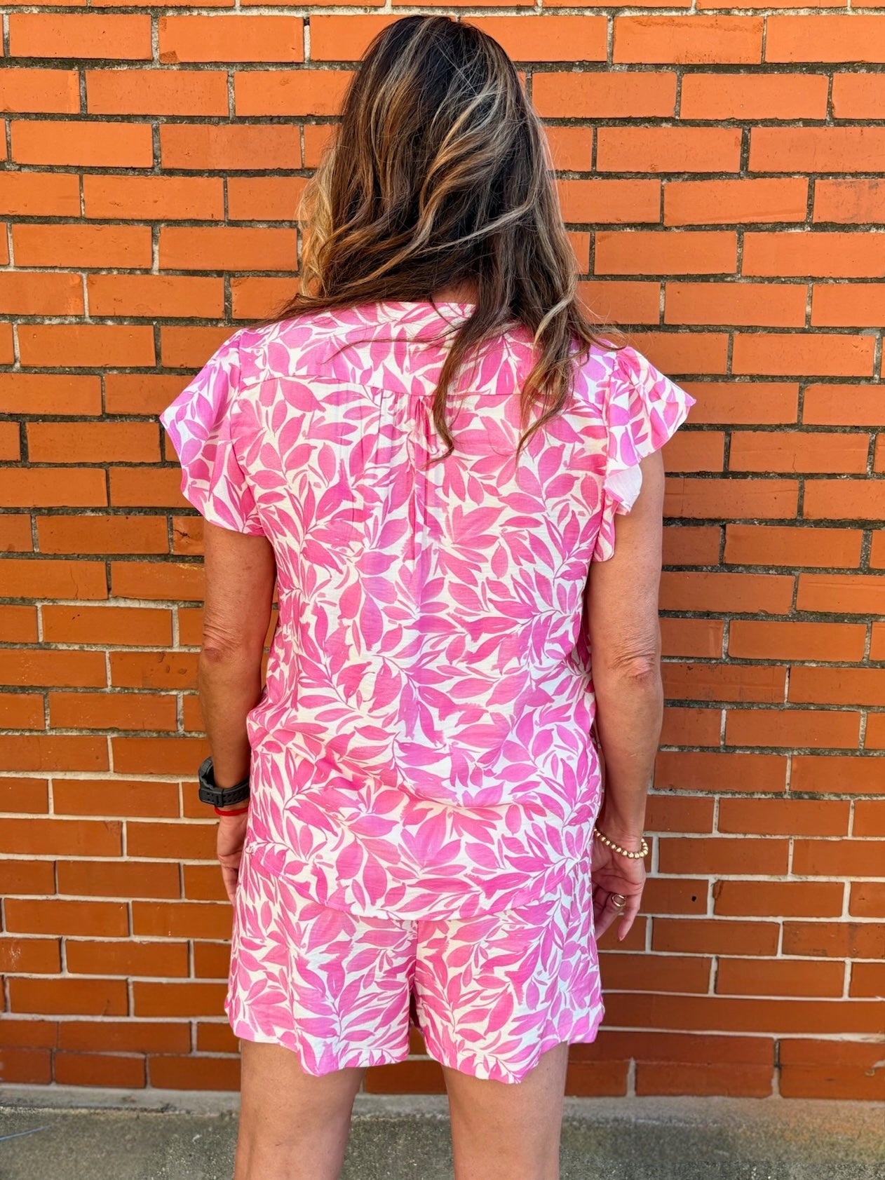 Flutter sleeve top, floral V-neck blouse, lightweight summer top, ruffled sleeve shirt, women’s botanical print top, pink floral blouse, breezy spring fashion. at ooh la la! in Grapevine TX 76051