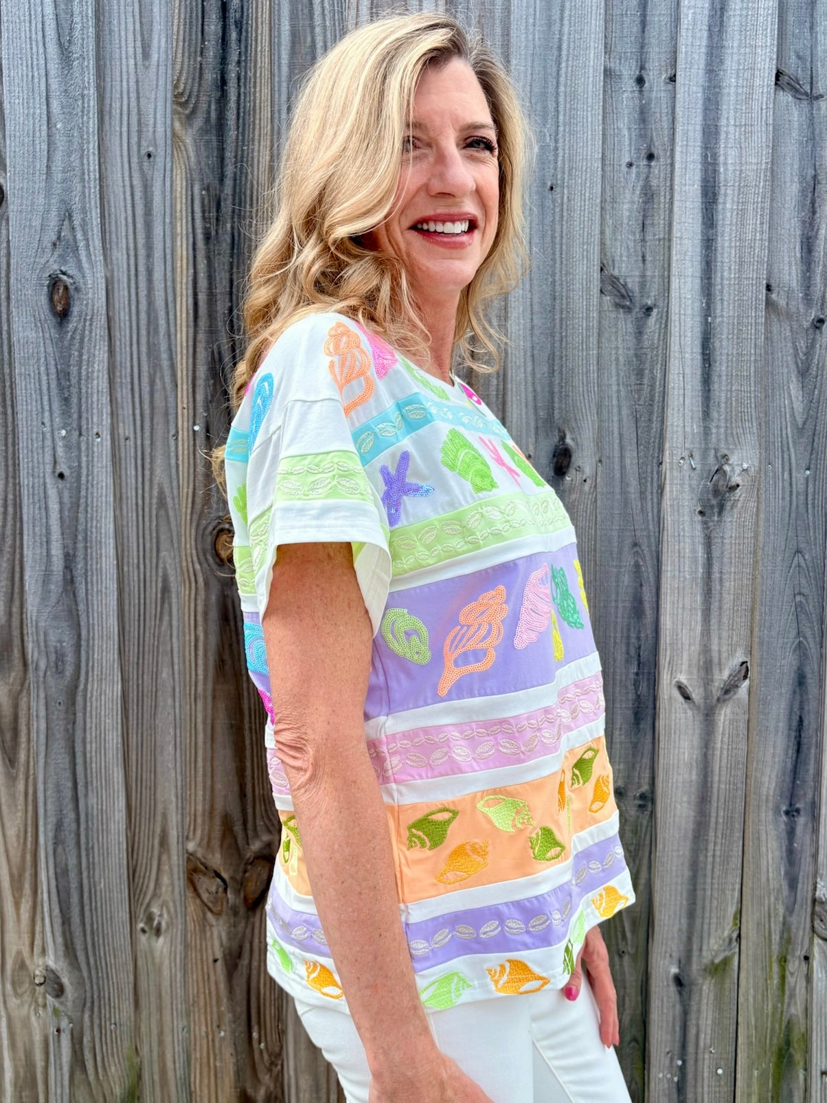 Queen of Sparkles, seashell sequin tee, pastel colorblock top, coastal vacation outfit, designer beach wear, sequin shell shirt, luxury summer fashion. at ooh la la! in Grapevine TX 76051