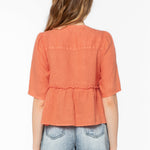 Back view of woman wearing coral orange Bevie top with denim shorts