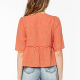 Back view of woman wearing coral orange Bevie top with denim shorts