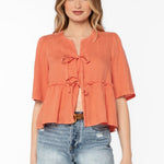 Woman wearing coral Bevie top with tie-front details and denim shorts