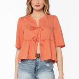 Woman wearing coral Bevie top with tie-front details and denim shorts