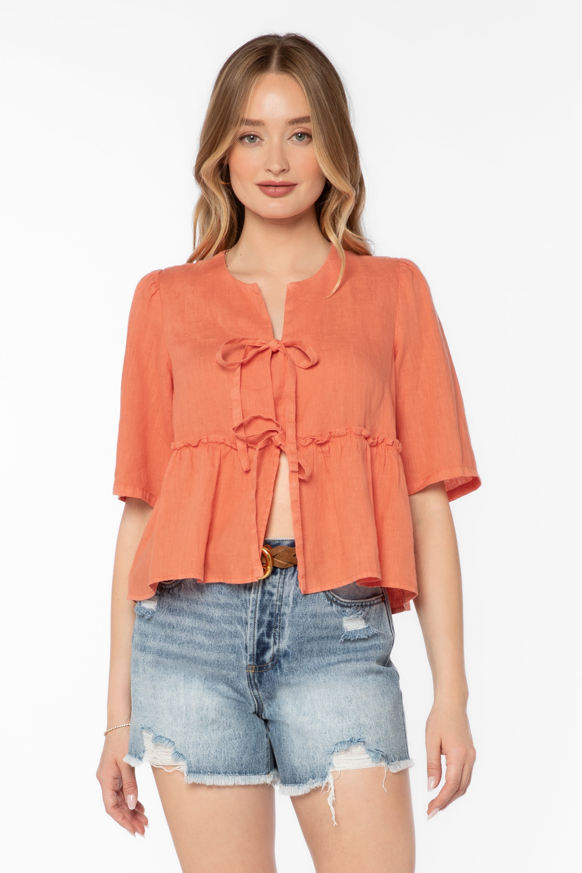 Woman wearing coral Bevie top with tie-front details and denim shorts