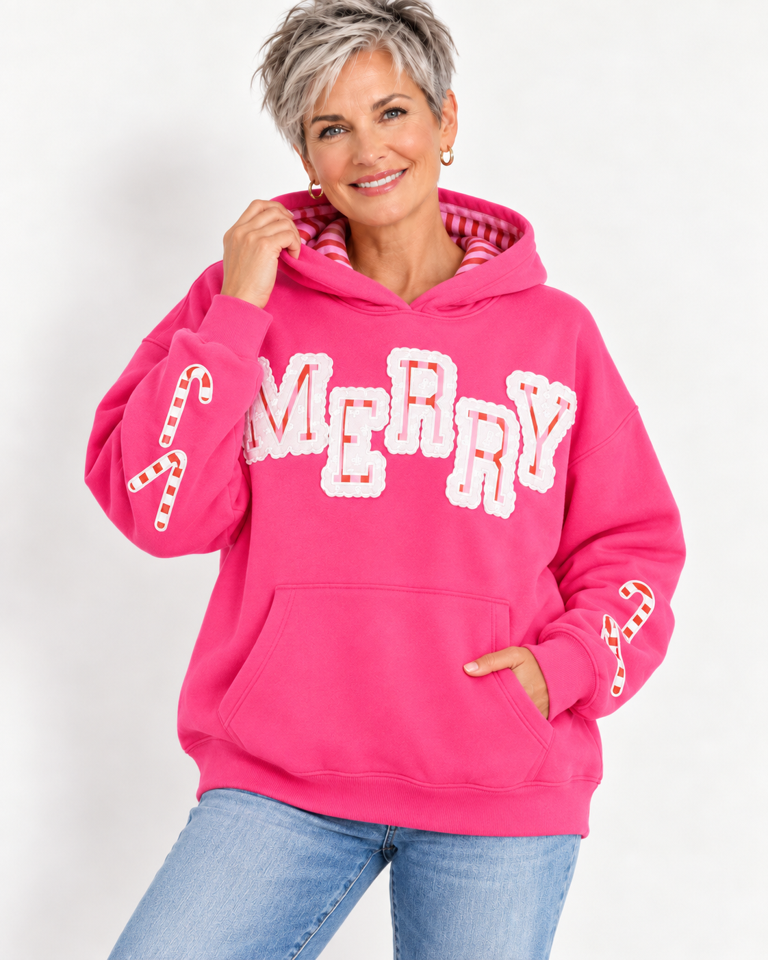 Woman wearing hot pink Simply Southern Merry appliqué hoodie with candy cane details at ooh la la! in Grapevine TX 76051
