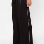Black satin wide-leg pants with cream side piping and drawstring waist on model