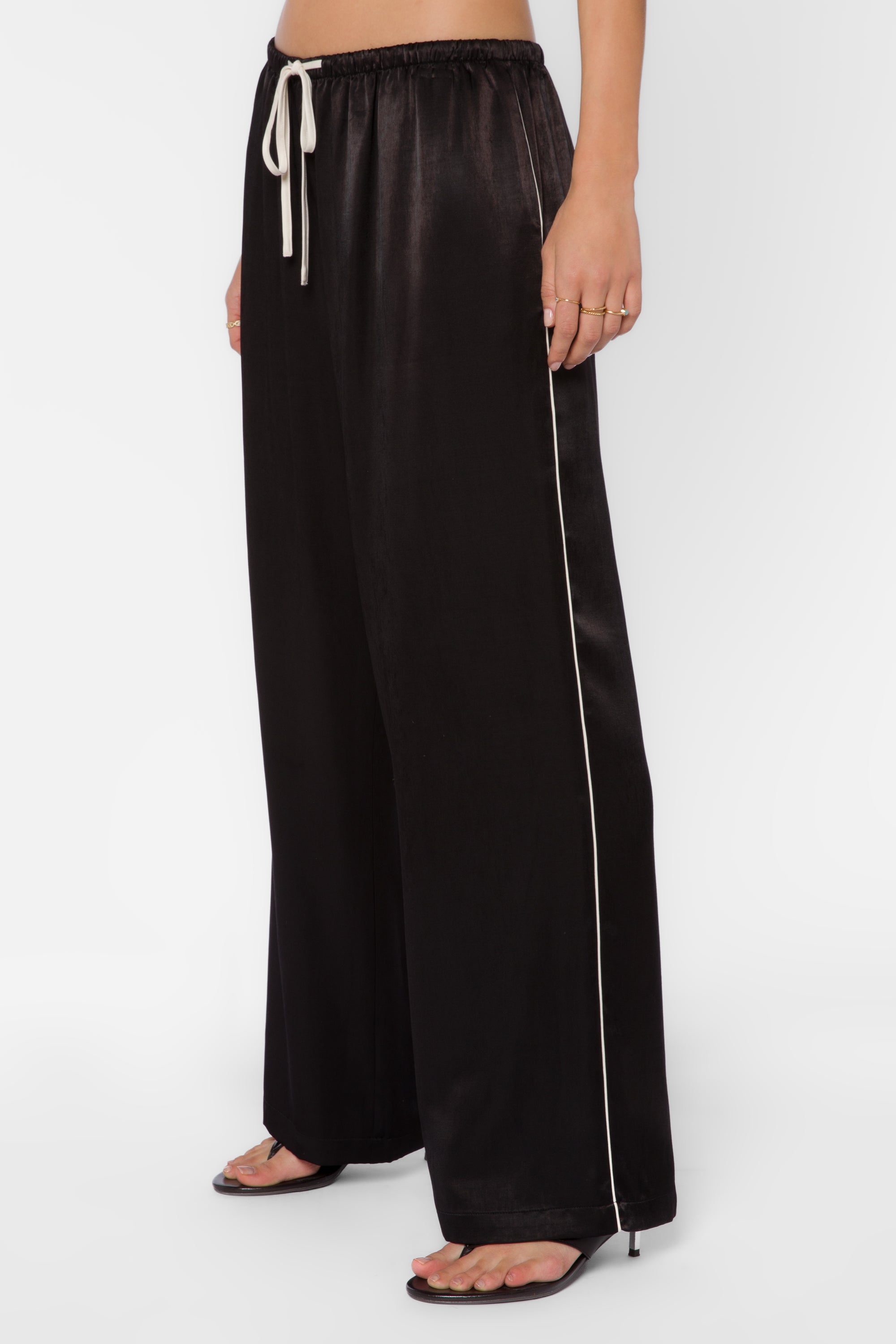 Black satin wide-leg pants with cream side piping and drawstring waist on model