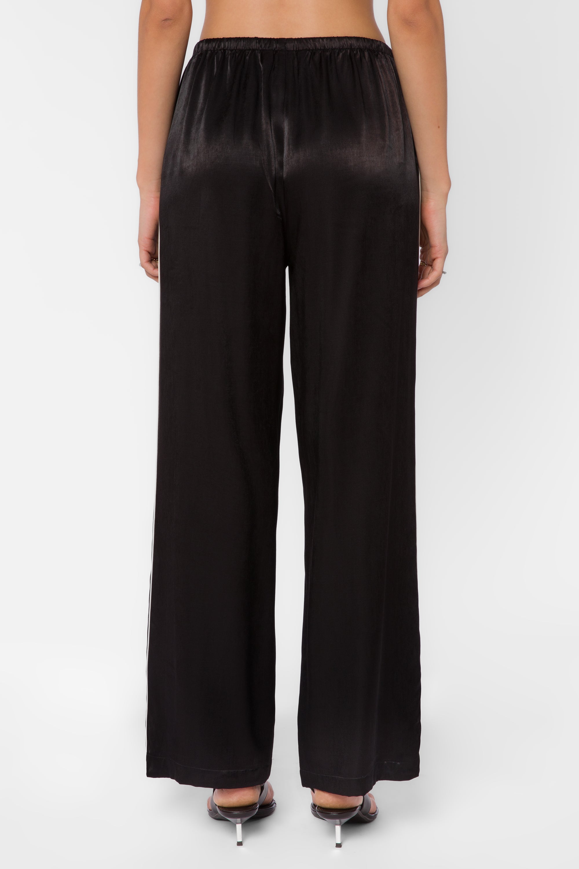 Back view of black satin wide-leg pants with elastic waist and side stripe detail