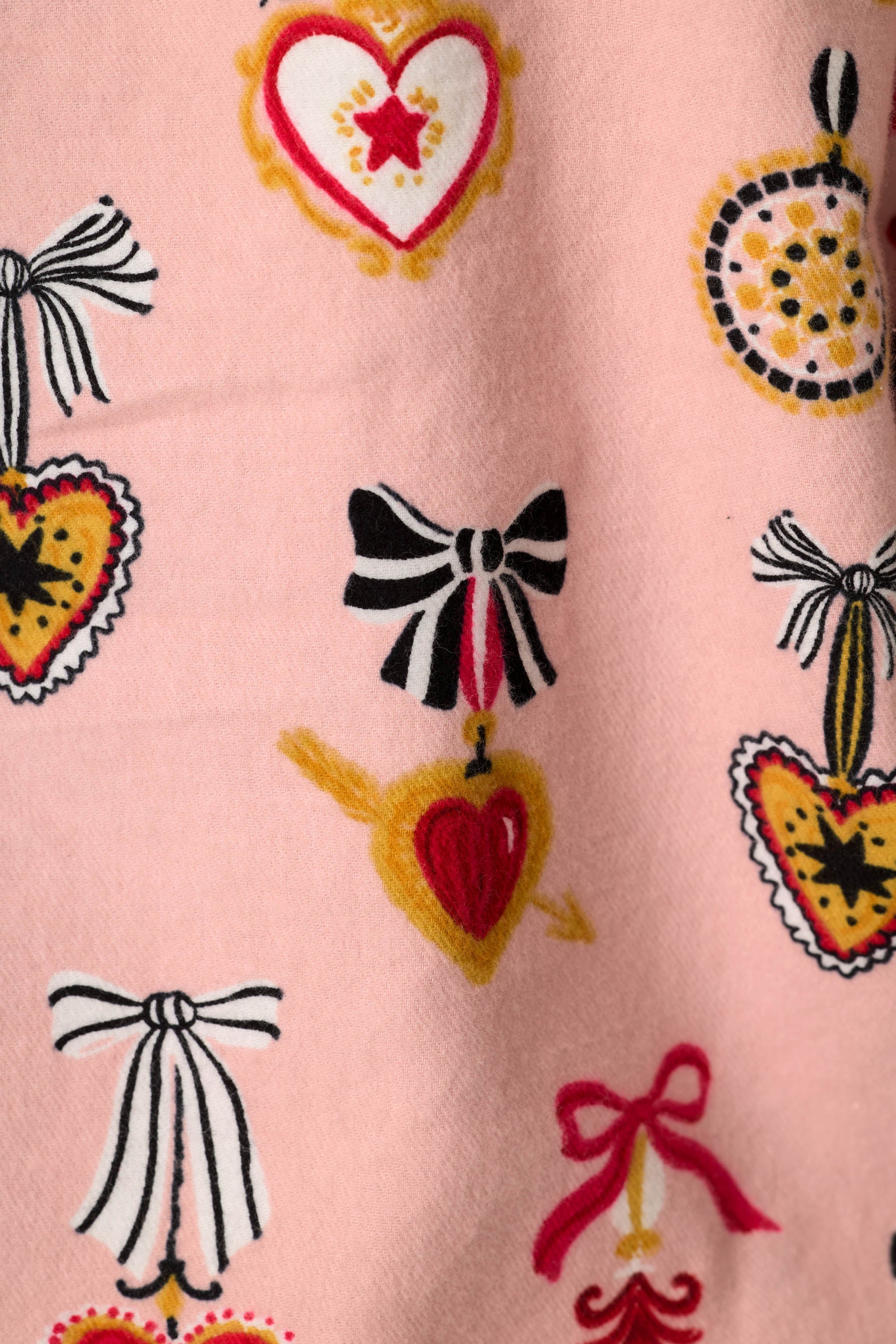 Close-up of PJ Salvage Love Lockets flannel print featuring hearts, bows, and lockets on pink background
