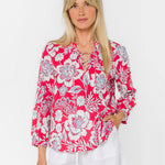 Woman wearing pink floral blouse with lace-up neckline and long sleeves