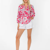 Woman wearing pink floral blouse with white shorts against white background