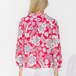 Woman wearing pink floral blouse with white shorts, back view studio shot