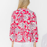 Woman wearing pink floral blouse with white shorts, back view studio shot