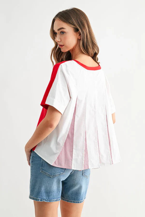 White blouse with red trim and pleated back detail worn with denim shorts