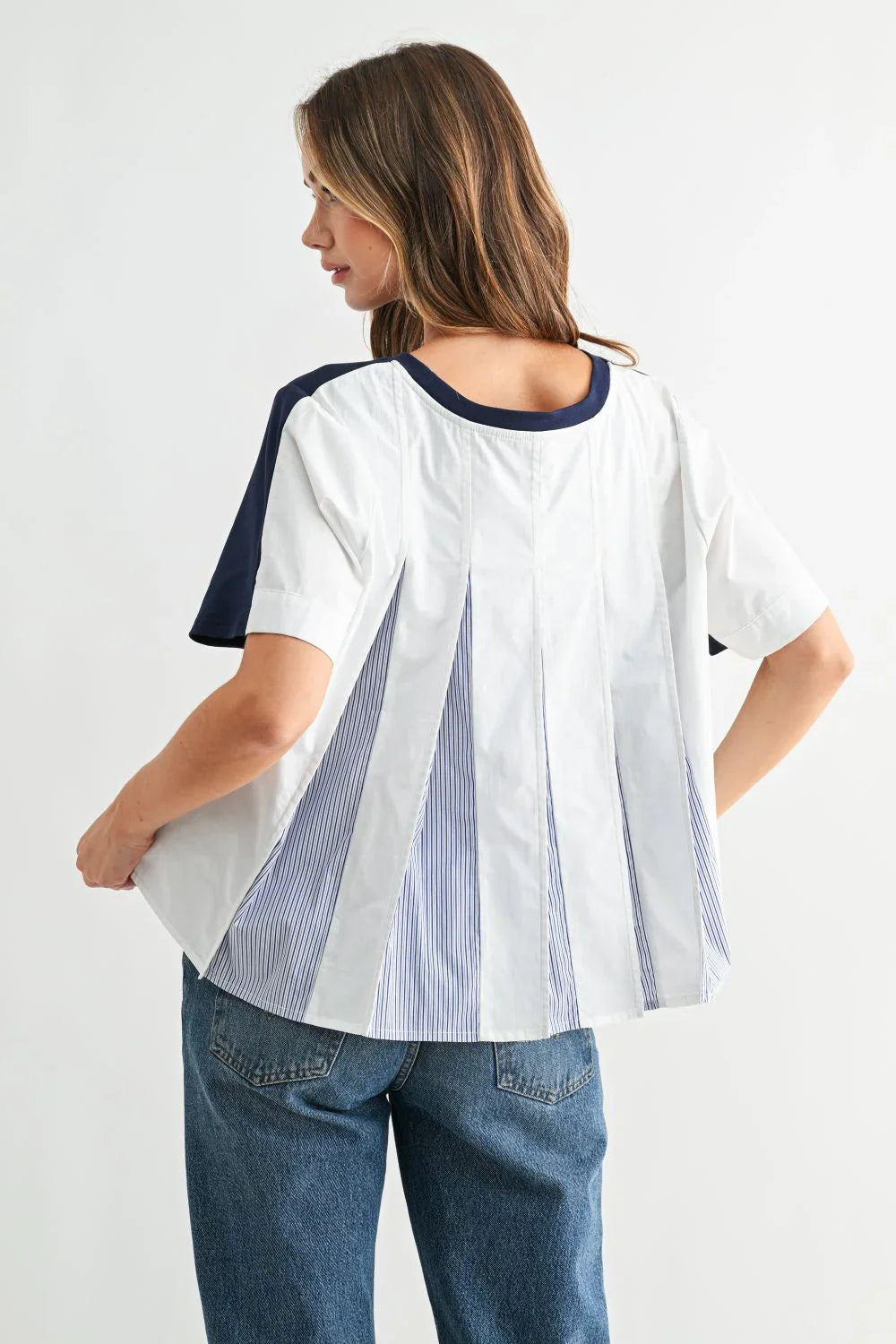 Woman wearing white tee with navy trim and blue striped pleat back detail