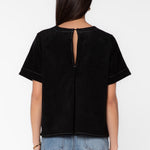 Back view of black suede short-sleeve shirt with keyhole opening on model
