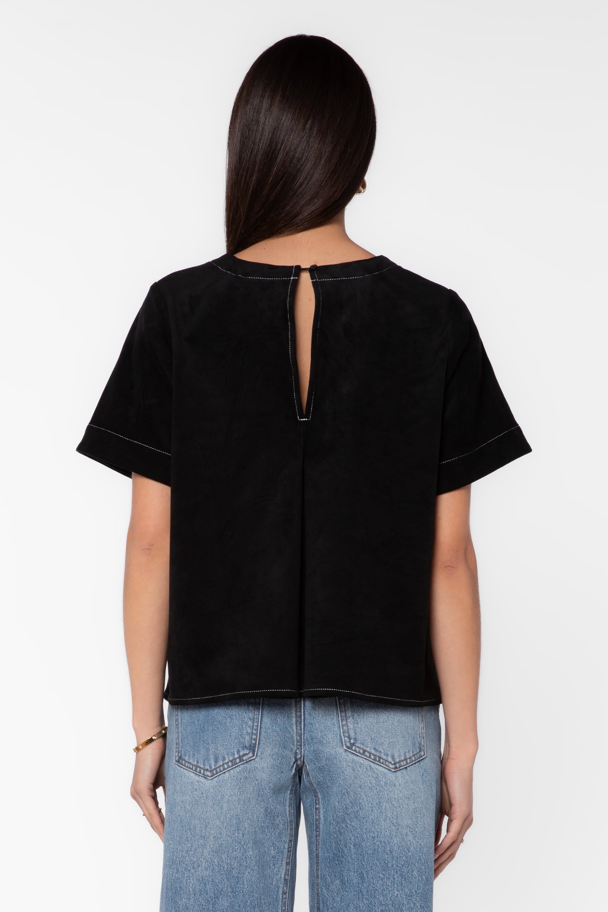 Back view of black suede short-sleeve shirt with keyhole opening on model
