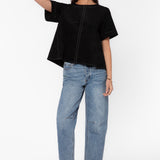 Woman wearing black oversized boxy shirt with contrast stitching and light wash jeans