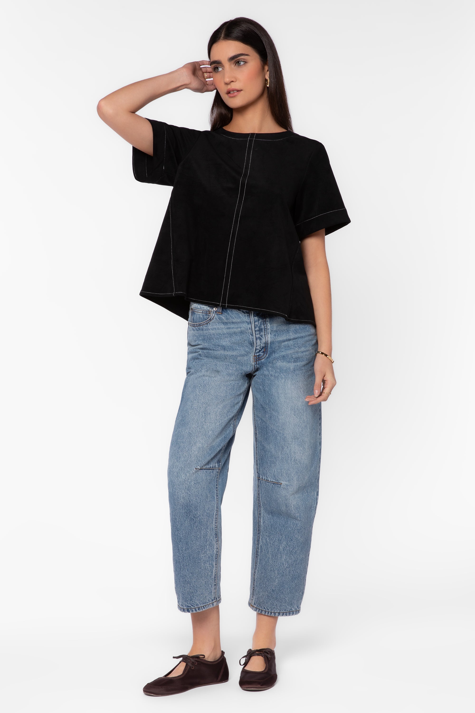 Woman wearing black oversized boxy shirt with contrast stitching and light wash jeans