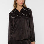 Woman wearing black satin western shirt with cream contrast trim and snap buttons