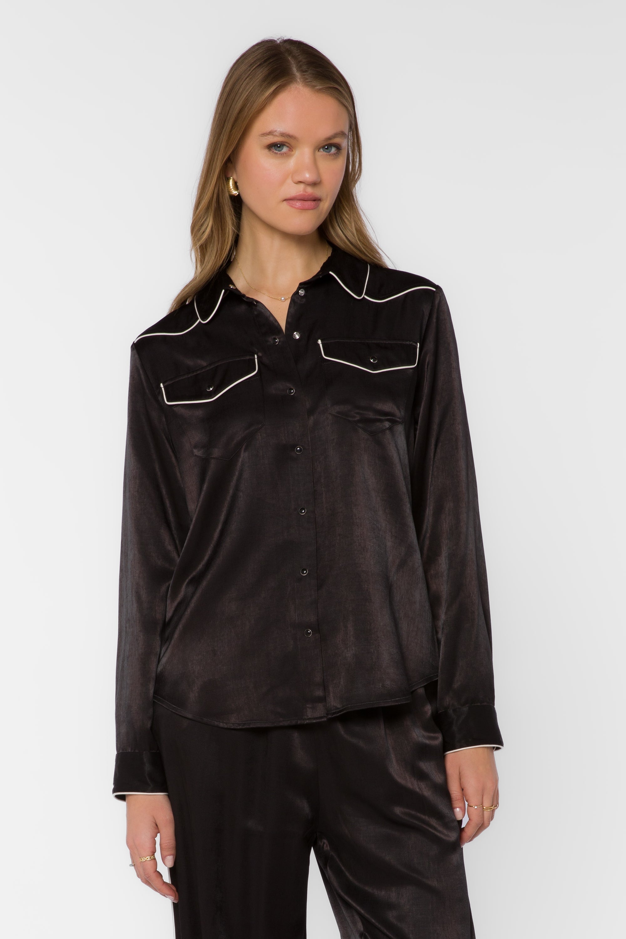 Woman wearing black satin western shirt with cream contrast trim and snap buttons