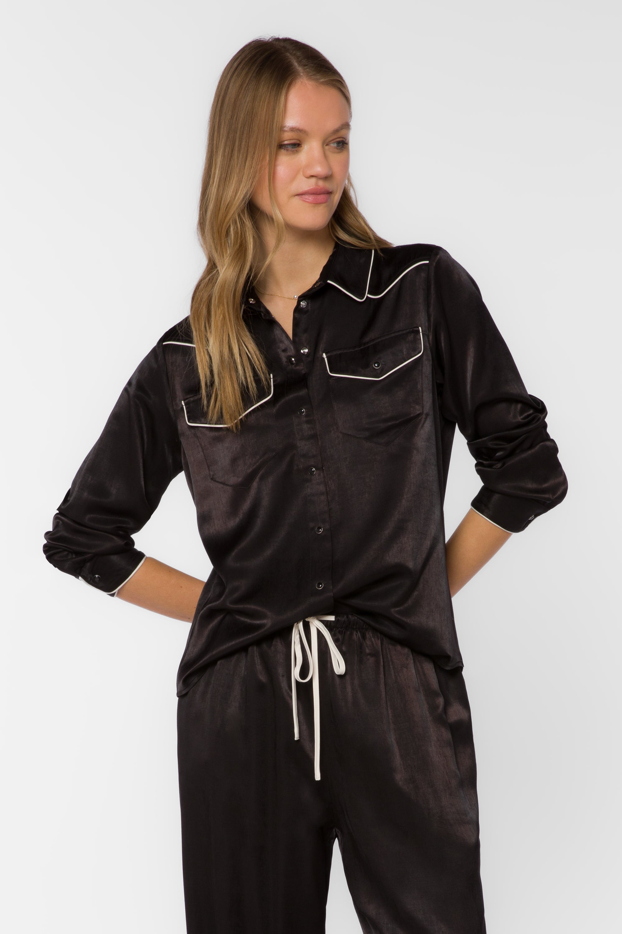 Woman wearing black satin western shirt with white contrast trim and snap buttons
