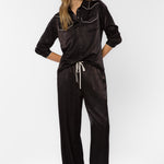 Woman wearing black satin western-style shirt with cream contrast trim and matching pants