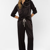 Woman wearing black satin western-style shirt with cream contrast trim and matching pants
