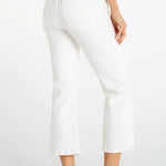 Woman wearing white cropped flare jeans with navy top and white sneakers