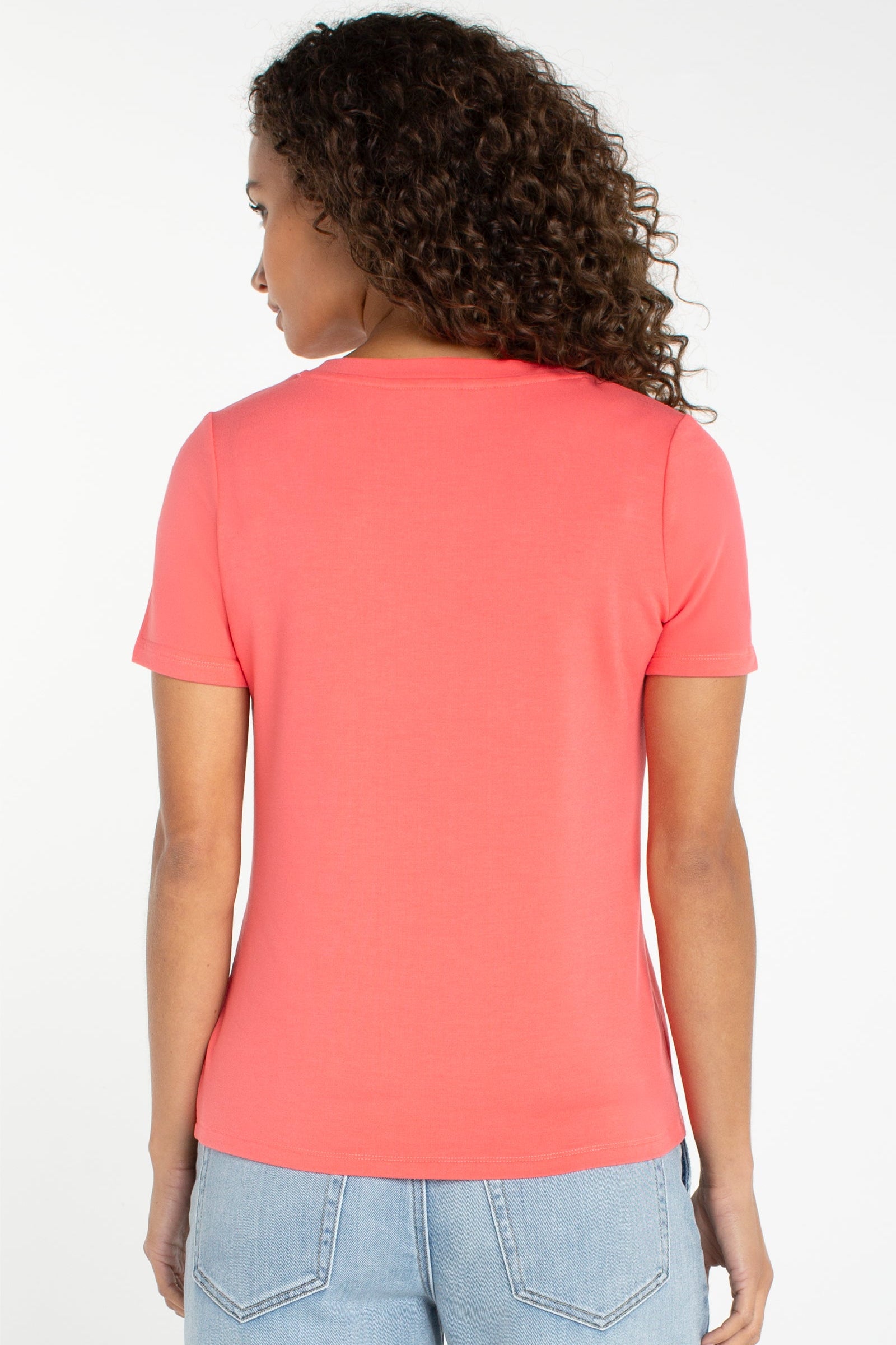 Women's short sleeve v-neck tee in sunset coral shown from the back view