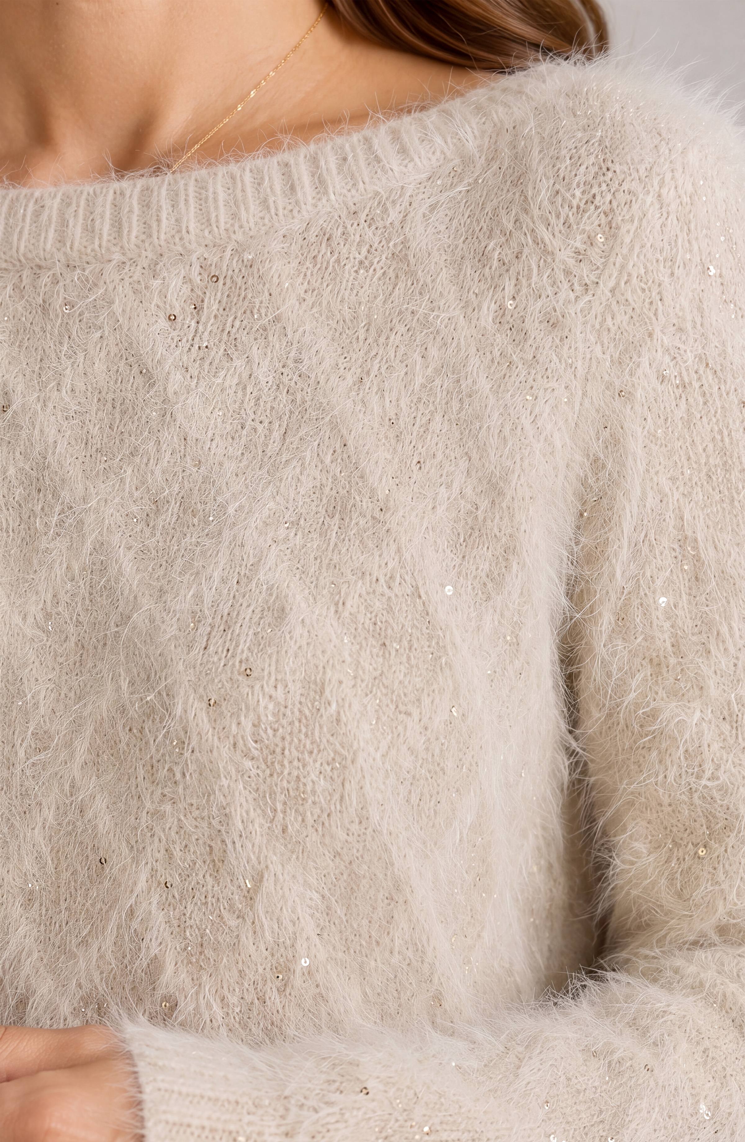 Close-up of a fuzzy boatneck sweater with scattered gold metallic sequin shimmer detail