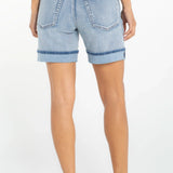 Woman wearing light blue denim cuffed shorts with rolled hems, back view