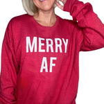 Close-up of a smiling woman wearing a bright red heathered crewneck sweatshirt with the bold white text "MERRY AF" printed across the front.