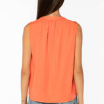 Back view of woman wearing coral sleeveless top with jeans