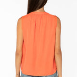 Back view of woman wearing coral sleeveless top with jeans