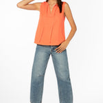 Woman wearing coral sleeveless top with tie neck detail and cropped jeans