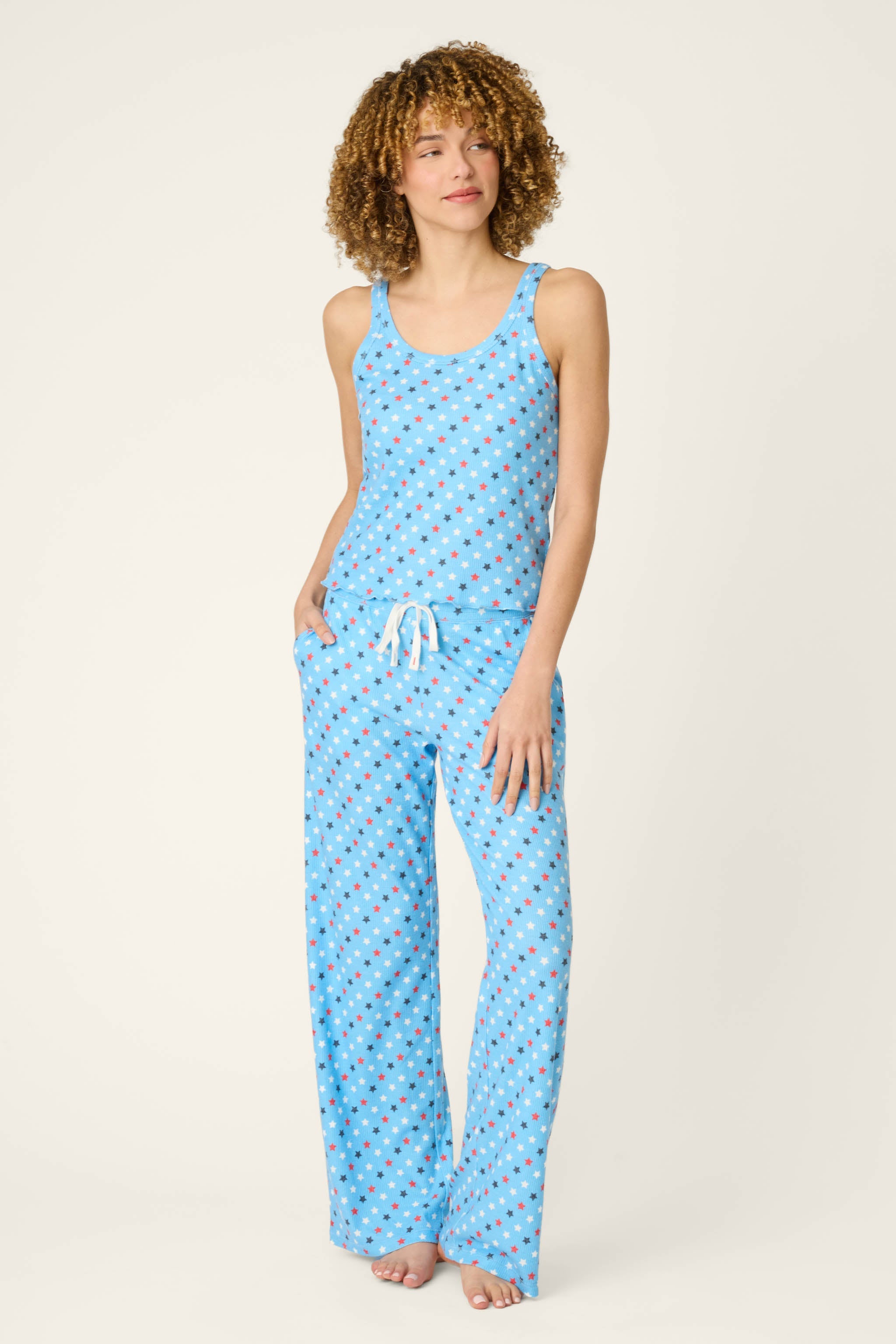 Woman wearing light blue pajama set with patriotic star print tank and pants