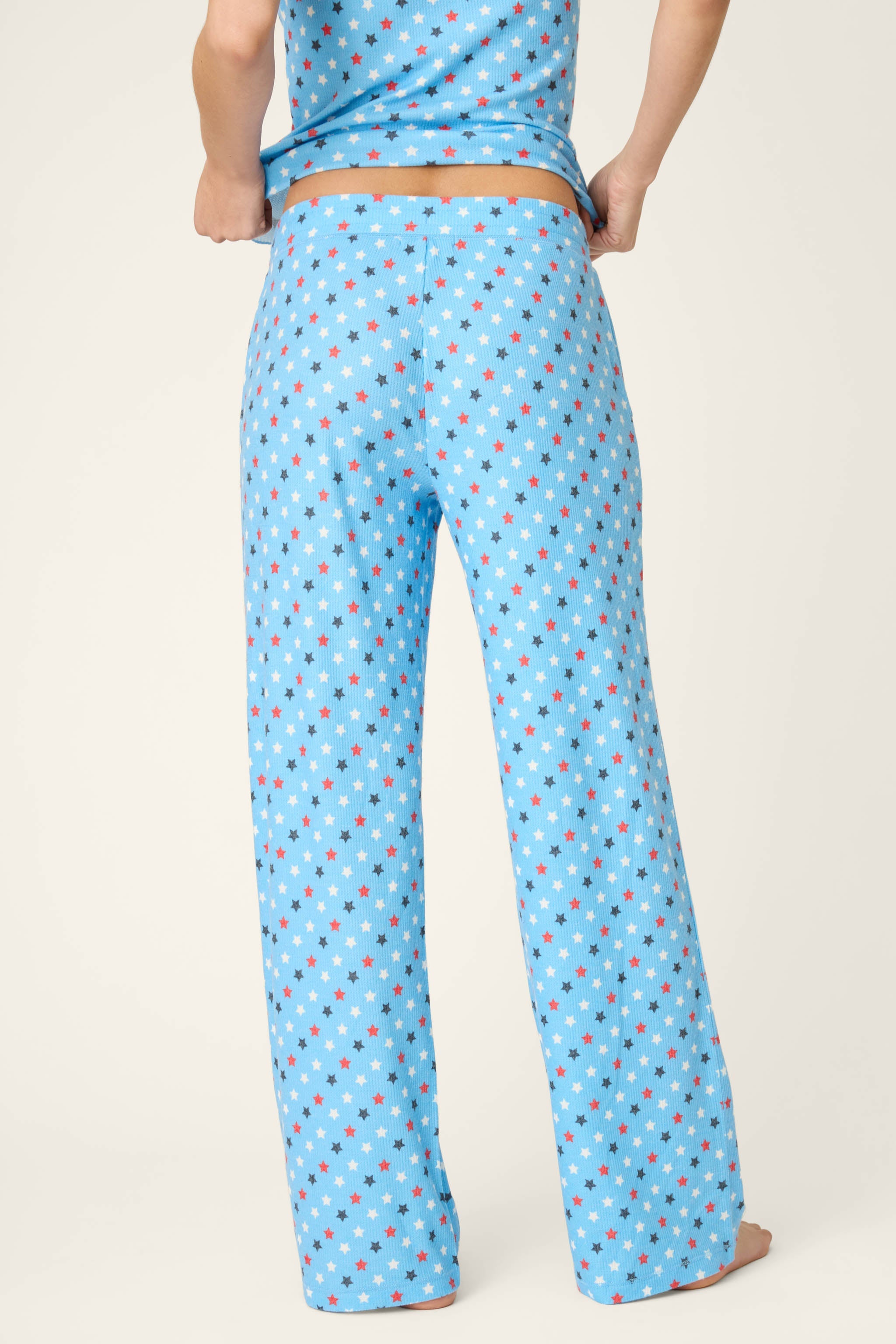 Light blue pajama pants with colorful star print pattern worn by model