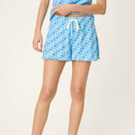 Woman wearing light blue star print pajama top and shorts set